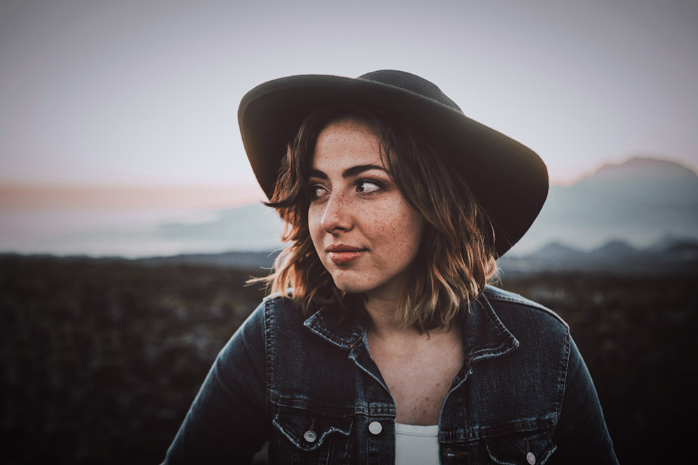 Youn woman in a hat looking to one side and smiling
