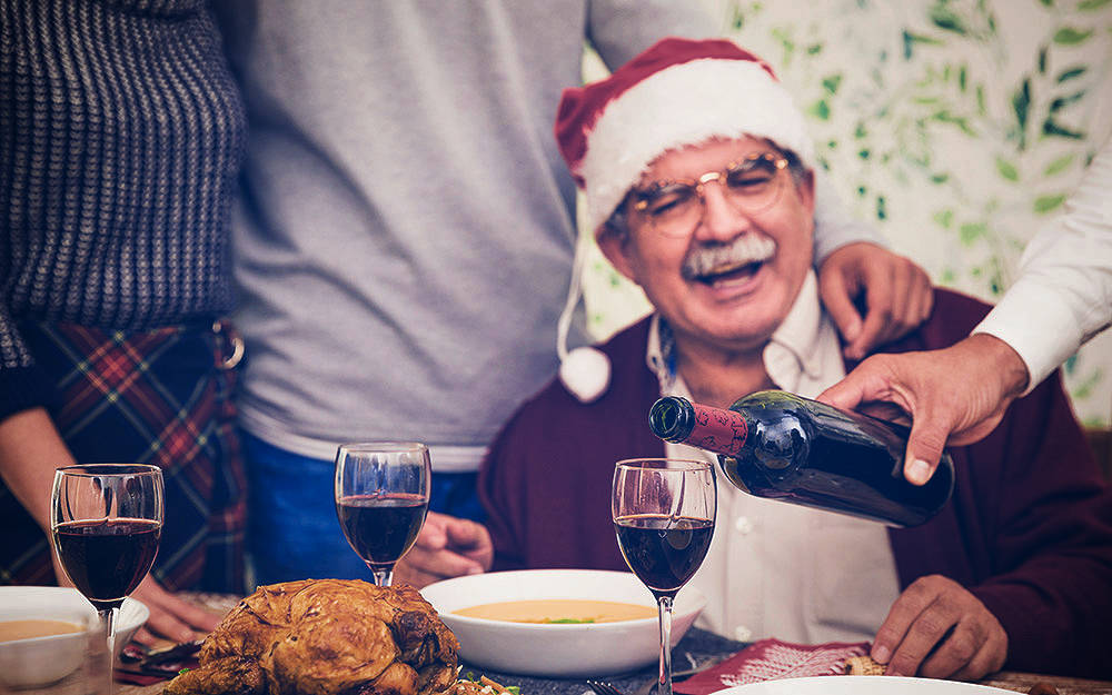 man filling the wine glass of a relative at the Christmas table
