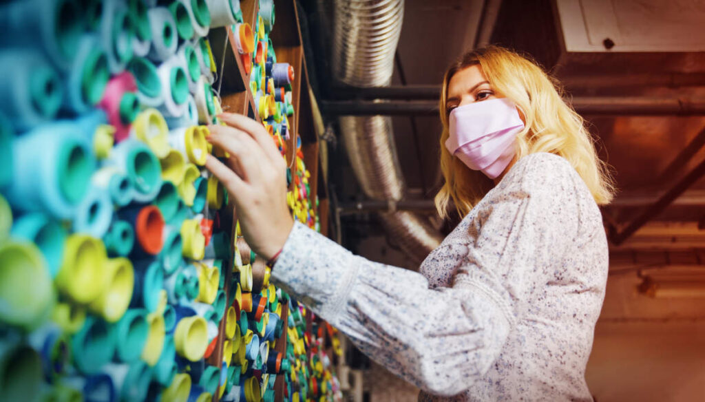 Woman wearing a PPE mask choosing coloured yarns