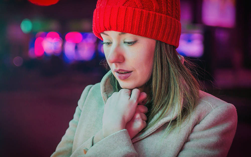 Young woman with a cold in red wool hat outside